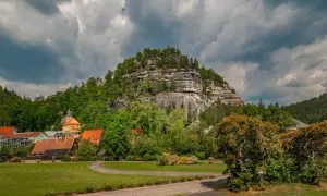 Ein malerischer tagesausflug sachsen mit einem Dorf am Fuße eines Felsmassivs und einer Kirche.