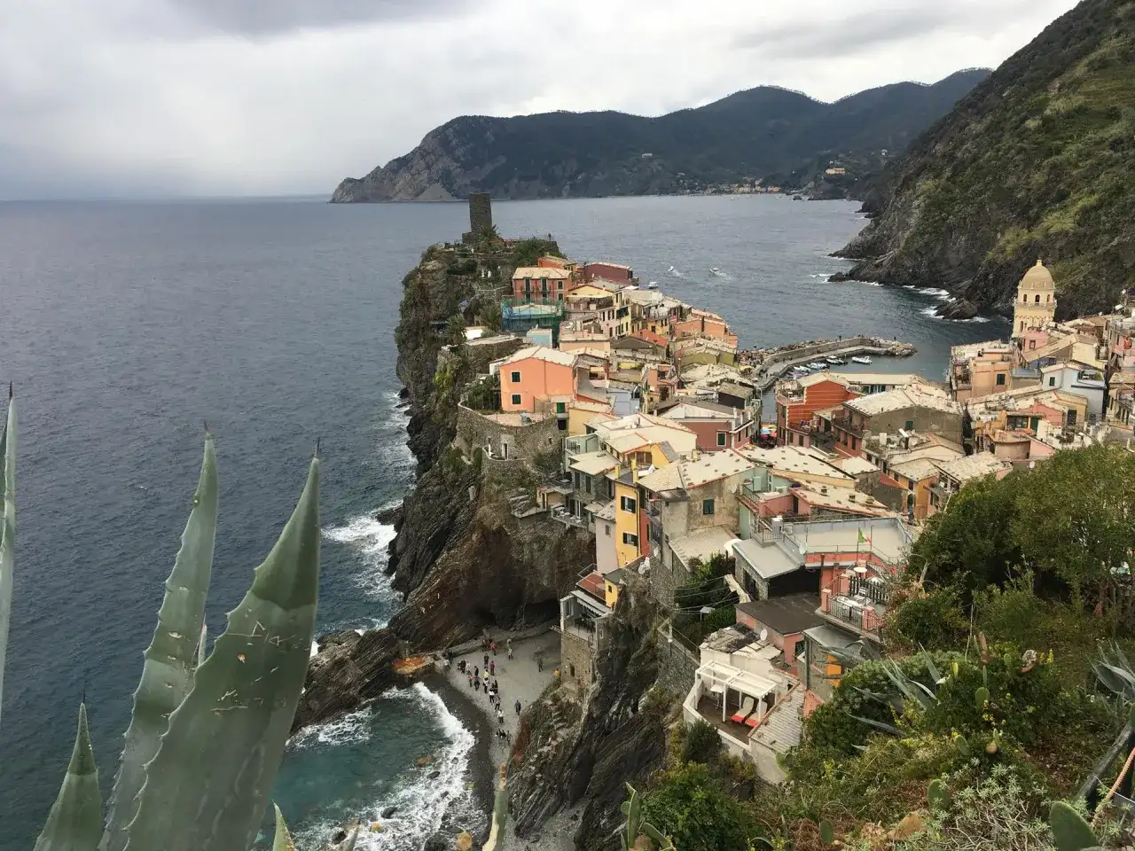 Bunte Häuser schmiegen sich an steile Klippen in Cinque Terre. Ein mittelalterlicher Turm wacht über die Bucht.
