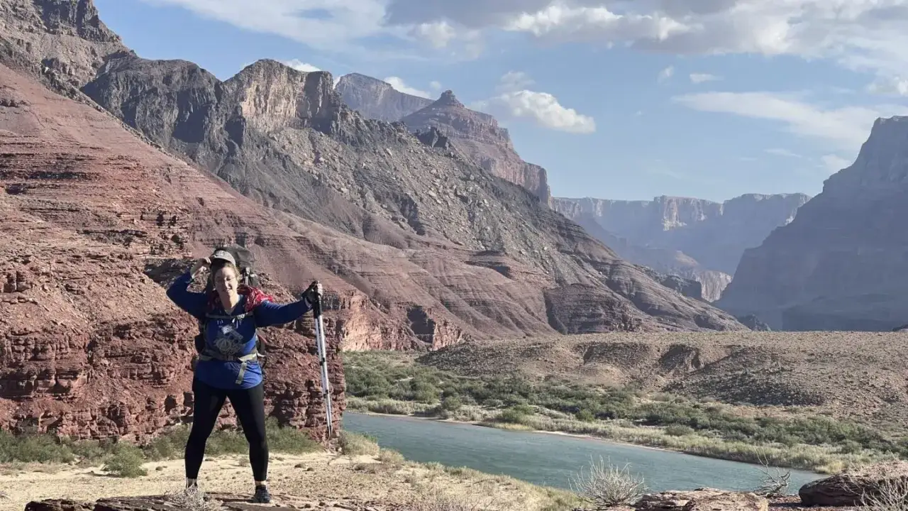 Wanderin im Grand Canyon National Park. Eine Frau mit Rucksack und Wanderstöcken steht vor der majestätischen Schlucht und dem Colorado River.